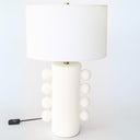 Side bobble ceramic table lamp with white textured ceramic base showing four circular bobbles on each side and brass neck finish