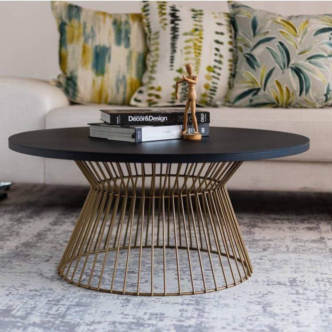 Round coffee table with bowtie base in gold in living room.