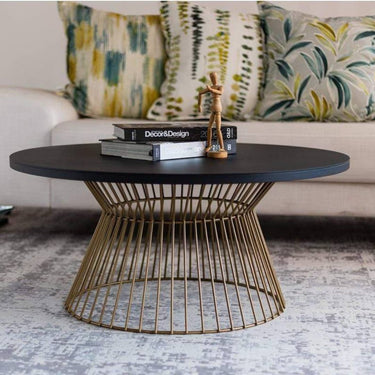 Round coffee table with bowtie base in gold in living room.