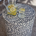 ound side table with bamboo core made from capiz shell in grey witha glass and jug in a home decor setting