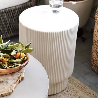 The drink table's natural matte white color and textured finish add a sculptural accent