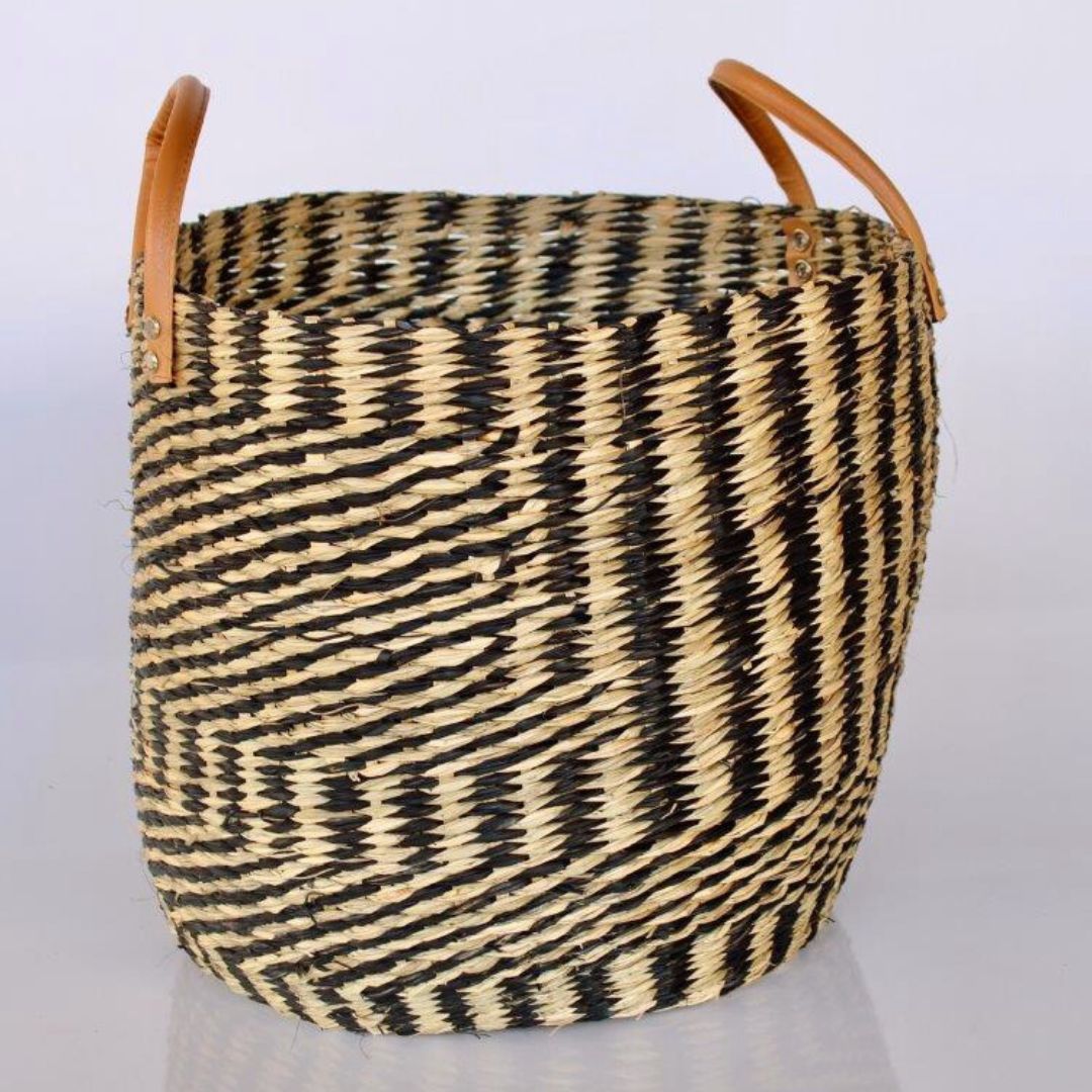 Stylish seagrass basket with tan leather handles for storage.