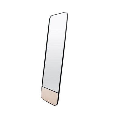 Modern full-length mirror leaning against a wall in a contemporary space.