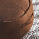 Boulder Stool in tan vinyl with round shape and high-density foam, ideal as a footrest, pouffe, or extra seat.