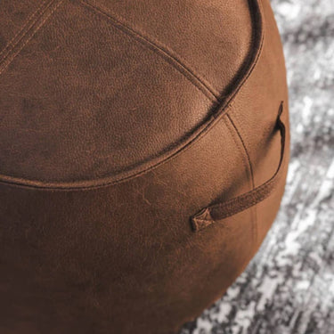 Boulder Stool in tan vinyl with round shape and high-density foam, ideal as a footrest, pouffe, or extra seat.
