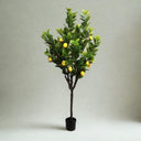 Artificial lemon tree with green leaves and yellow lemons on a plain background