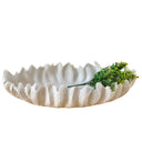 Large white ceramic bowl with scalloped edge and ribbed texture, styled with leaves.