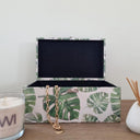 green decorative box with botanical design on entryway open shelf.