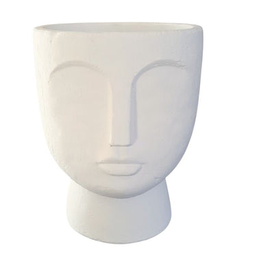 A white concrete face planter with a stylized human face design, suitable for housing plants.