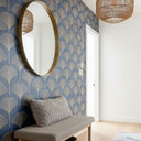 Entryway showing a gold circular mirror hung at the correct height on a a feature wall and a woven pendant light.