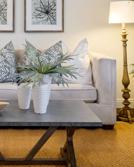 Bright and airy living room styled with spring decor ideas, featuring a light jute rug, botanical wall art, lighting and fresh greenery by Woodka Interiors