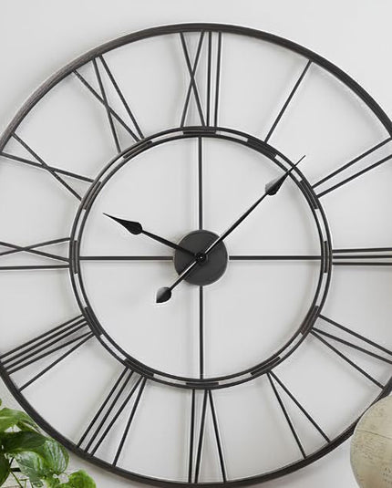 Large open-frame skeleton metal wall clock hung as a functional art centerpiece on a neutral living room wall.