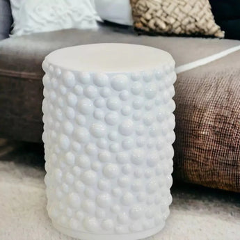 White ceramic stool in a living room, perfect for enhancing your space with versatile seating. Featured in the designer stools and benches collection at Woodka Interiors.