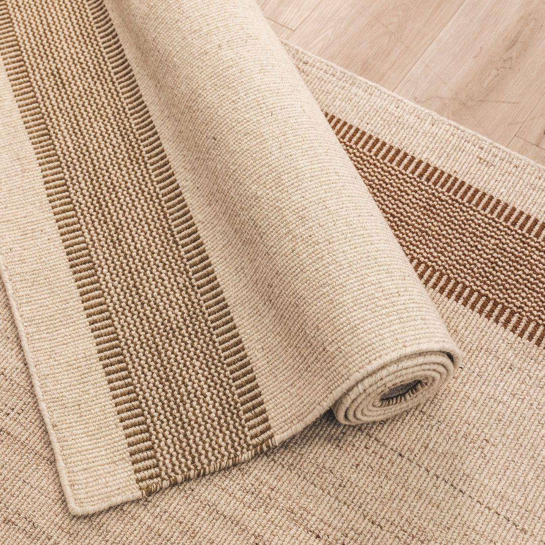 Beige woven rug with a textured pattern on a wooden floor.