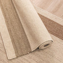 Beige woven rug with a textured pattern on a wooden floor.