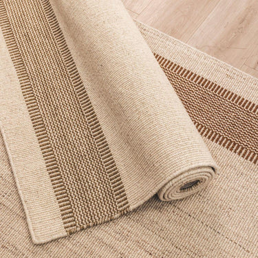 Beige woven rug with a textured pattern on a wooden floor.