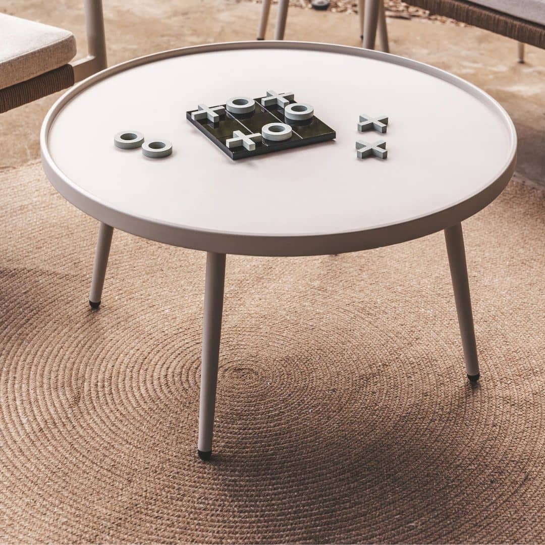 Round white coffee table with decorative items on a Carousel Round Outdoor Rug in maple 