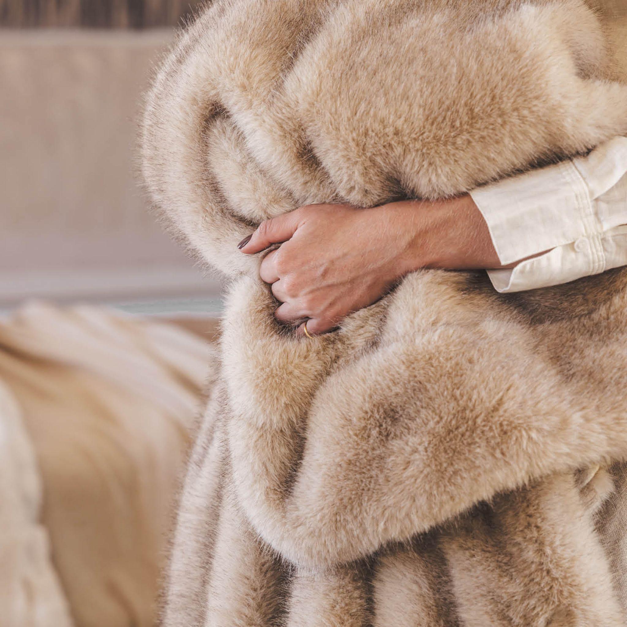 Coyote Fuux fur throw close-up holding the beige blanket