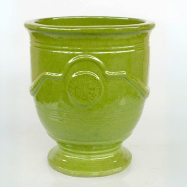 Green planter pots with a classic wreath emblem design for garden or home decor.
