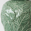 Close-up of embossed botanical detailing on green ceramic lamp base