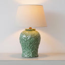 Green botanical ceramic table lamp illuminated on a console