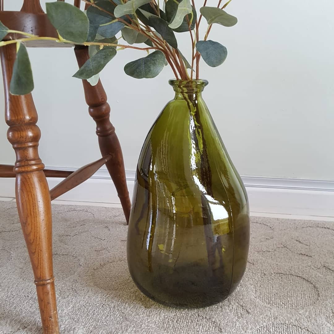 Large glass vase on the floor with eucalyptus stem