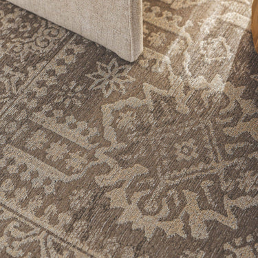 A close-up of a Memoir sepia traditional area rug with an ornate floral and geometric pattern in taupe, brown, and beige rug
