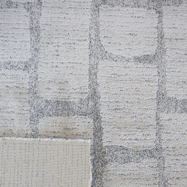 close up of milestone area rug with a gray and white geometric interlocking block pattern.