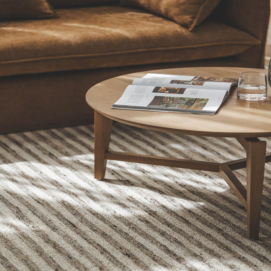 The Molteno Oak Coffee Table styled entrepiece in a modern living room as a solid oak round coffee table on a rug net to a brwon couch