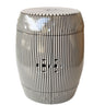 Modern black and white vertical striped ceramic drum stool with double-coin cutouts on a white background.