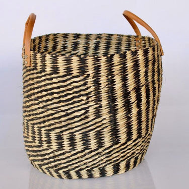 Stylish seagrass basket with tan leather handles for storage.