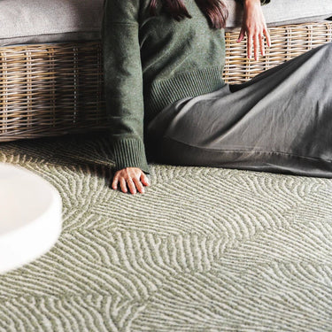 A green geometric patterned outdoor rug with a shell-like design