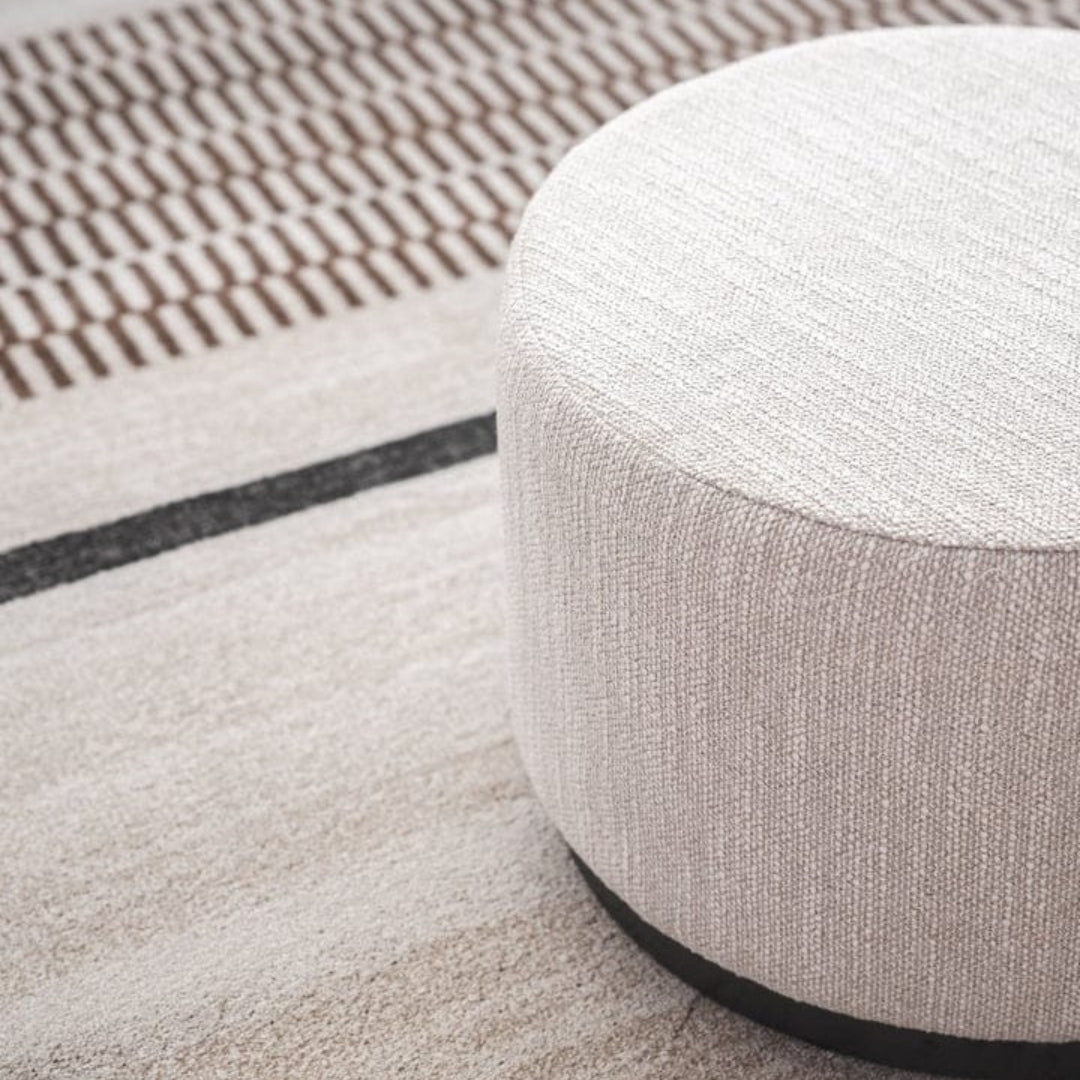 Solace Ottoman in a round shape and soft, sandy hue