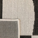 Close-up of a talon rug with a black and off-white geometric pattern.