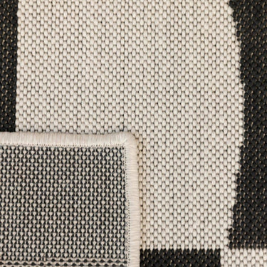 Close-up of a talon rug with a black and off-white geometric pattern.