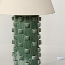Green textured table lamp with a beige lampshade on a white background