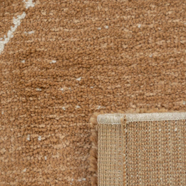 a Vagabond geometric area rug in the camel brown Dryland, showing the plush loop pile texture and backing fold