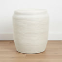 White rattan stool side table on a wood floor in a neutral room
