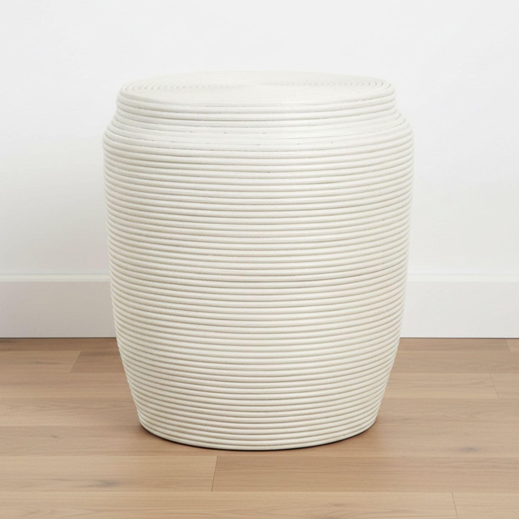 White rattan stool side table on a wood floor in a neutral room