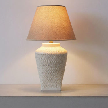 Textured white ceramic table lamp illuminated on a console