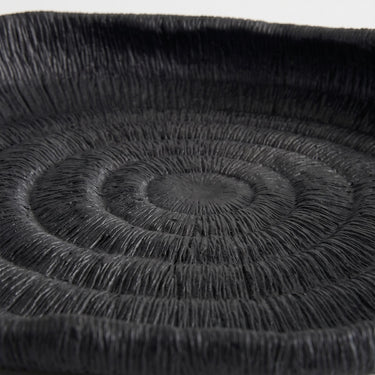 Deep black oval ribbed tray with a fine, textured surface and a raised rim.
