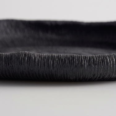 Deep black oval ribbed tray edge with a fine, textured surface and a raised rim.