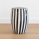 A  Black striped side table styled as a sculptural focal point in a minimalist studio setting.