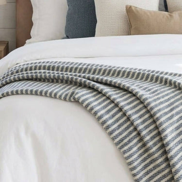 Extra large Celine Lagoon blue and cream accent blanket draped over a bed.
