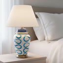 The Blue Swirl Lamp providing a warm soft glow on a bedside table in a coastal-inspired bedroom setting.