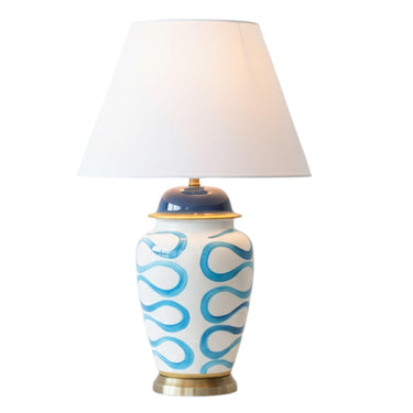 The Blue Swirl Lamp featuring a handcrafted white ceramic base with an artistic hand-painted pattern and white fabric shade.