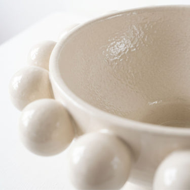 Cream ceramic pedestal bowl with large decorative bobble accents on rim.