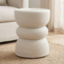 A modern three-tier side table with a ribbed rattan textured finish in a warm off-white colour, styled on a woven jute rug in a living room setting.