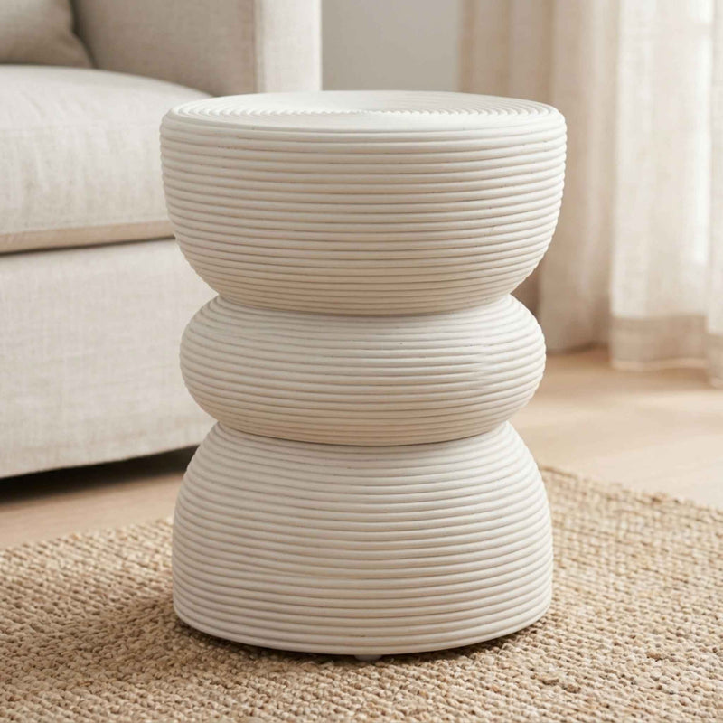 A modern three-tier side table with a ribbed rattan textured finish in a warm off-white colour, styled on a woven jute rug in a living room setting.