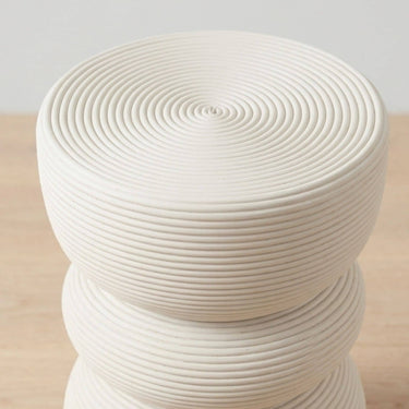 A modern round rattan side table with a stacked design and circular ribbed texture.